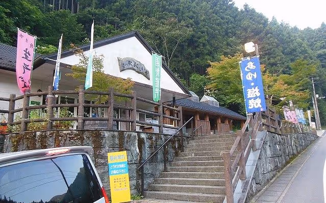 Traditional Japanese building on a hillside with stairs leading up and colorful vertical banners along the entrance.