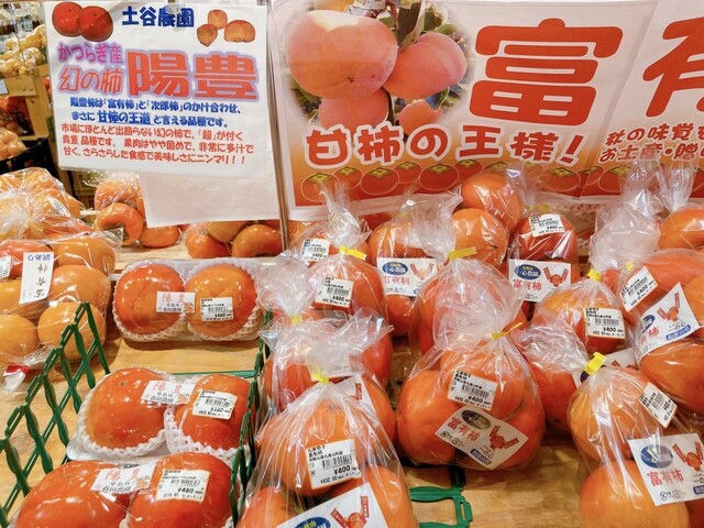 Market display of packaged bright orange persimmons with Japanese labels and signs.