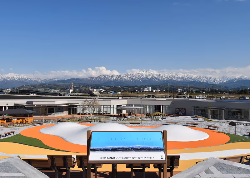 Outdoor visitor center with a colorful playground and snow-capped mountains in the background under a clear blue sky.