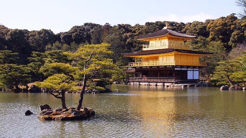 Golden Pavilion temple reflected in a pond with trees surrounding the water.