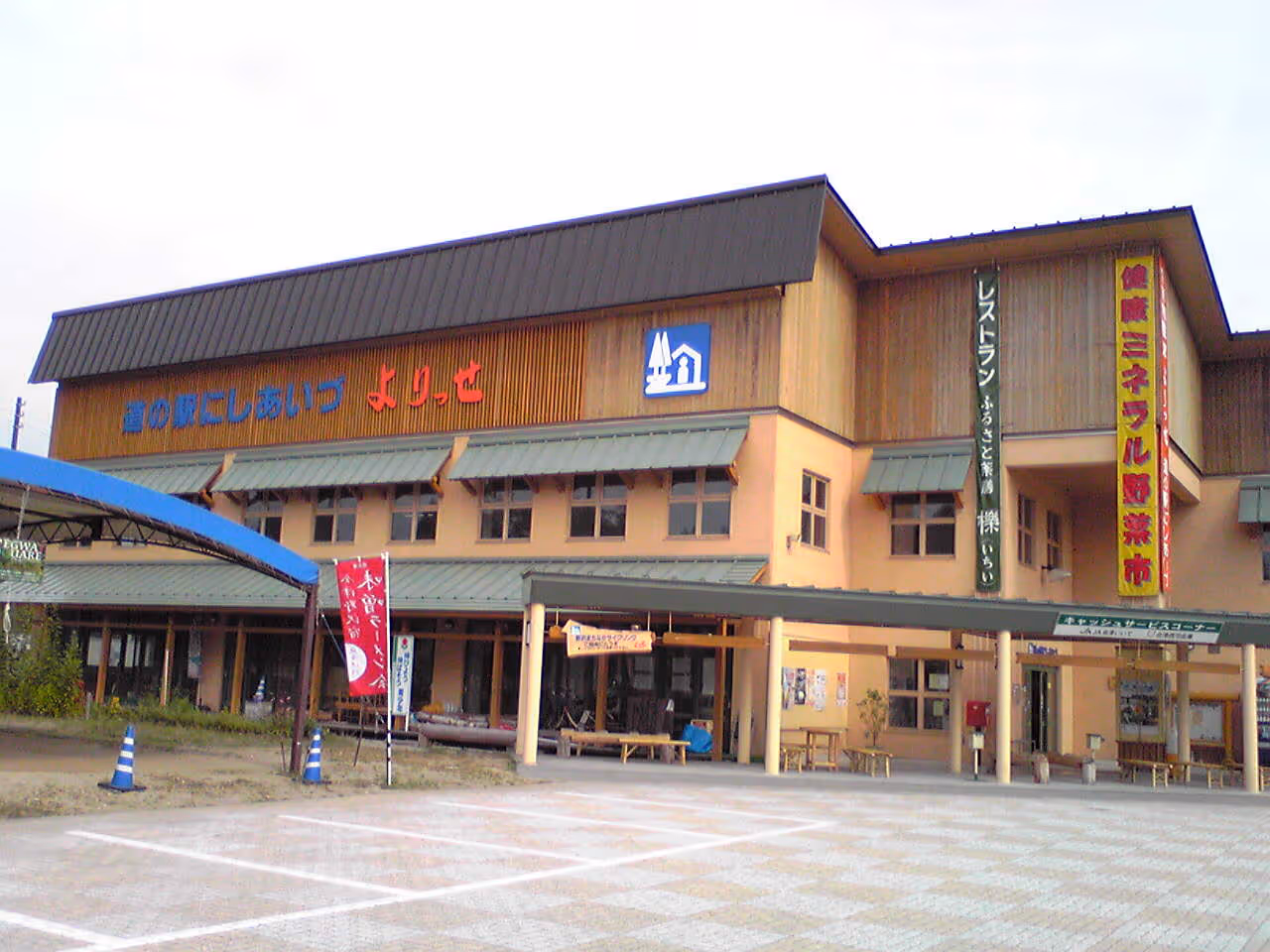 Exterior view of a beige and wood-paneled building with Japanese signage and a covered entrance area.