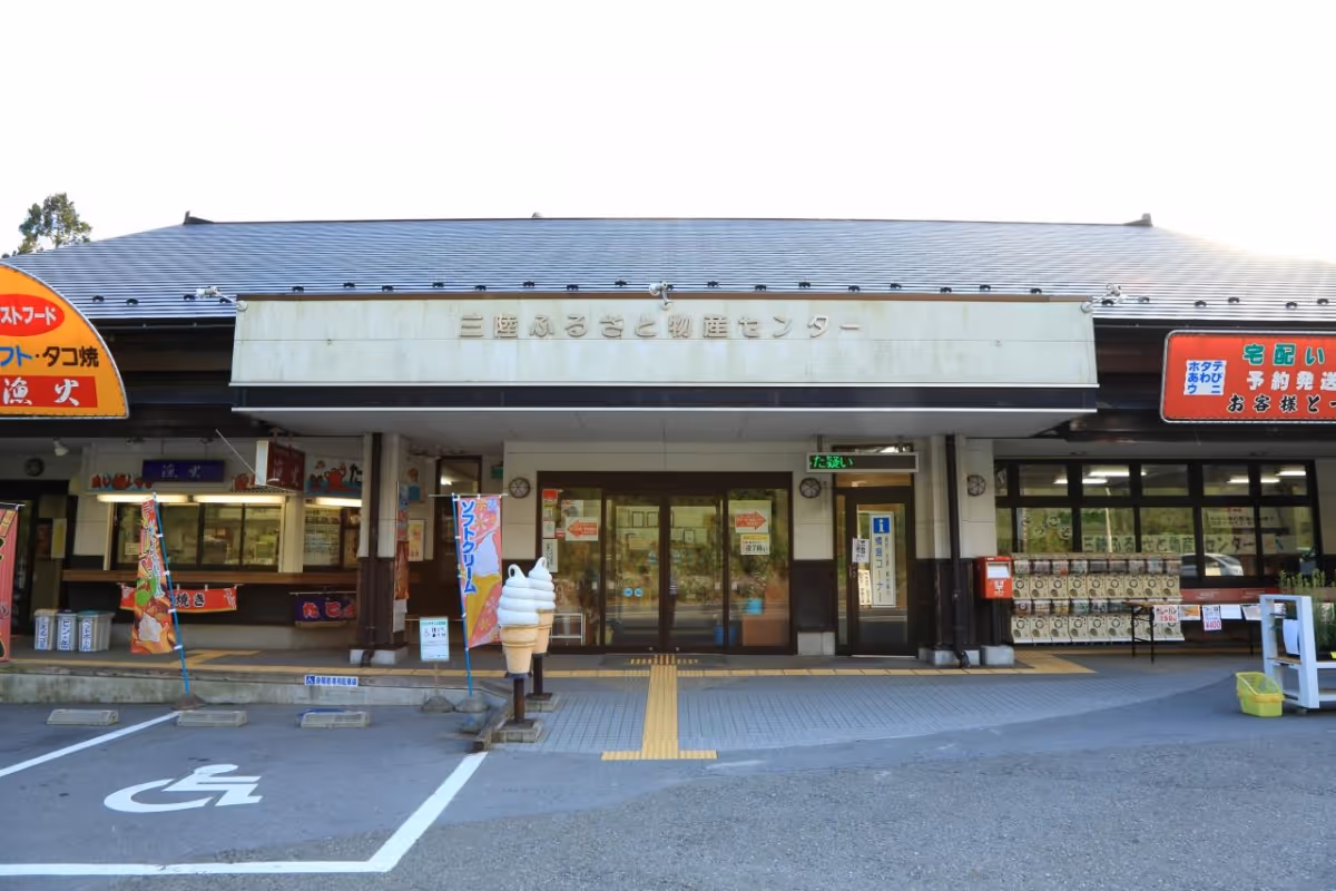Front entrance of a Japanese building with signs, vending machines, ice cream cone statues, and a handicapped parking space.