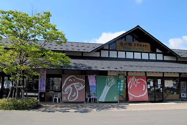 Traditional Japanese building with banners featuring illustrations of a mushroom, green onion, and tomato under a clear sky.