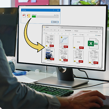 Computer monitor displaying a file saving progress bar for a PDF file and a folder window showing multiple PDF and one Excel file icons.