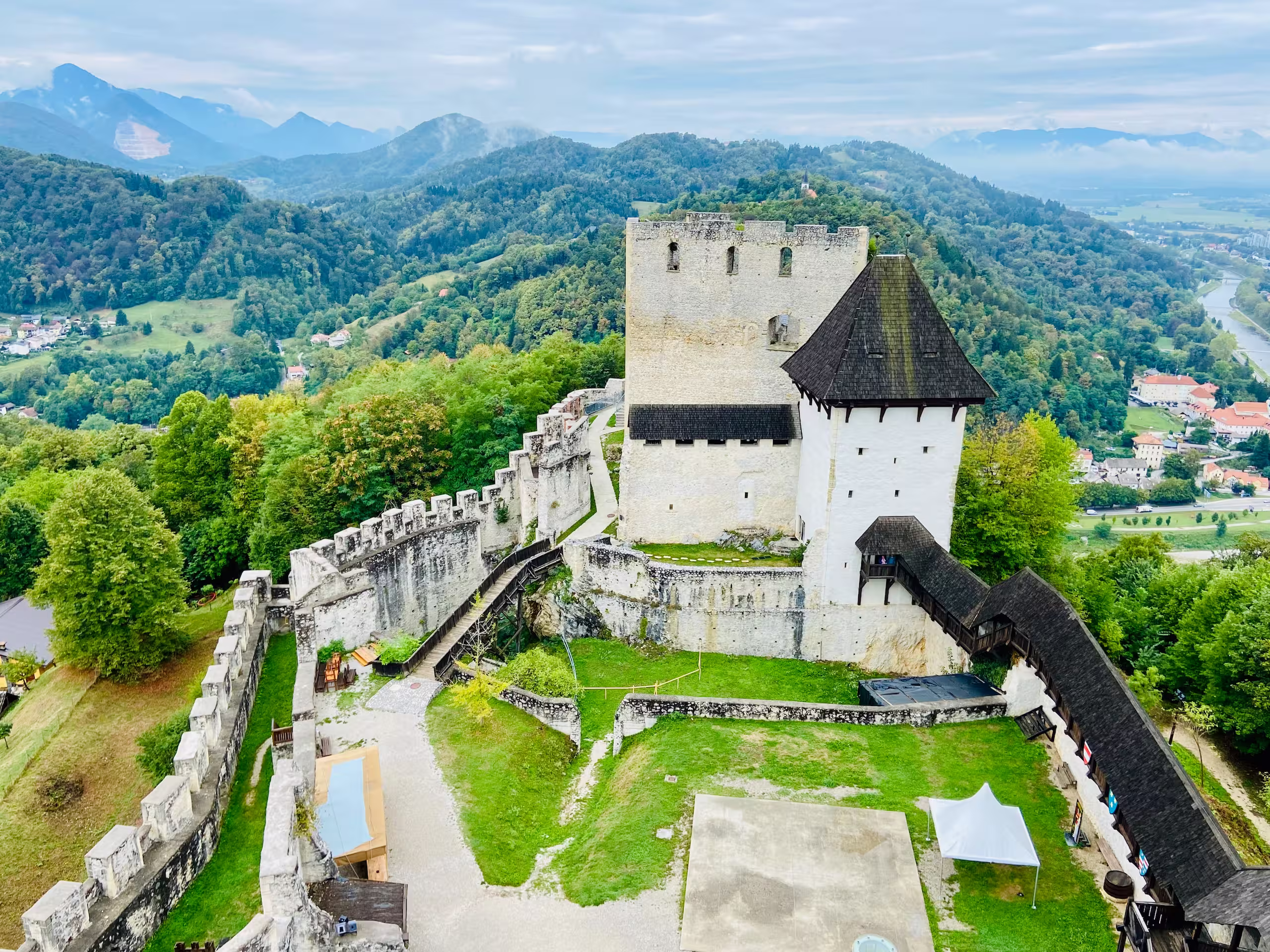 De muren en torens van het Stari grad boven Celje, omringd door bossen in herfstkleur.