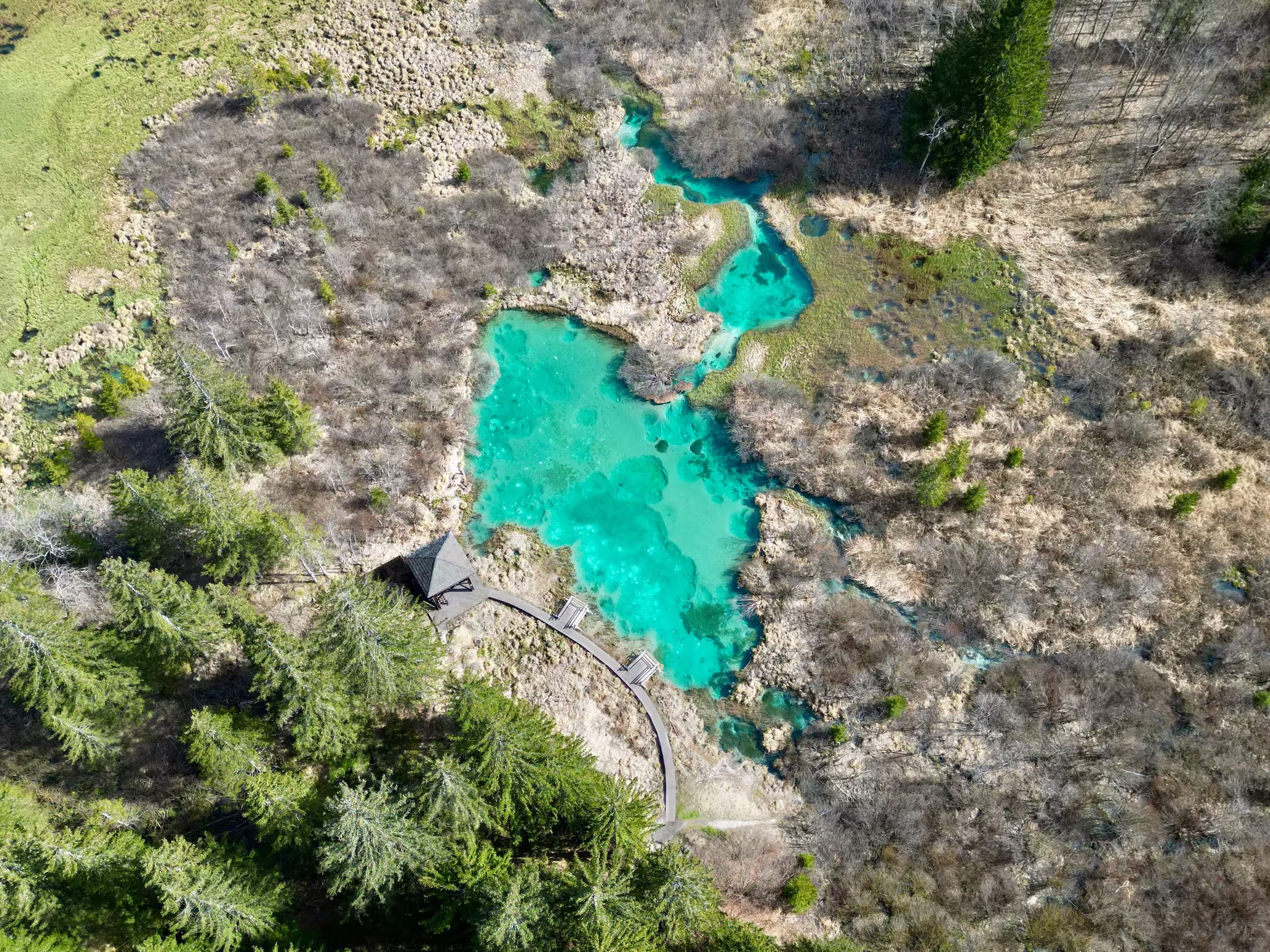 Emerald green lake from above with a wooden path and a view point