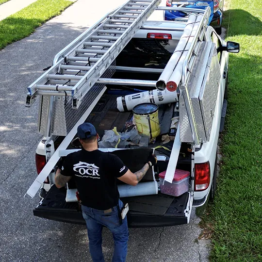 OCR Roofing technician preparing roof repair materials from a work truck in Oviedo, FL before starting a residential roof repair