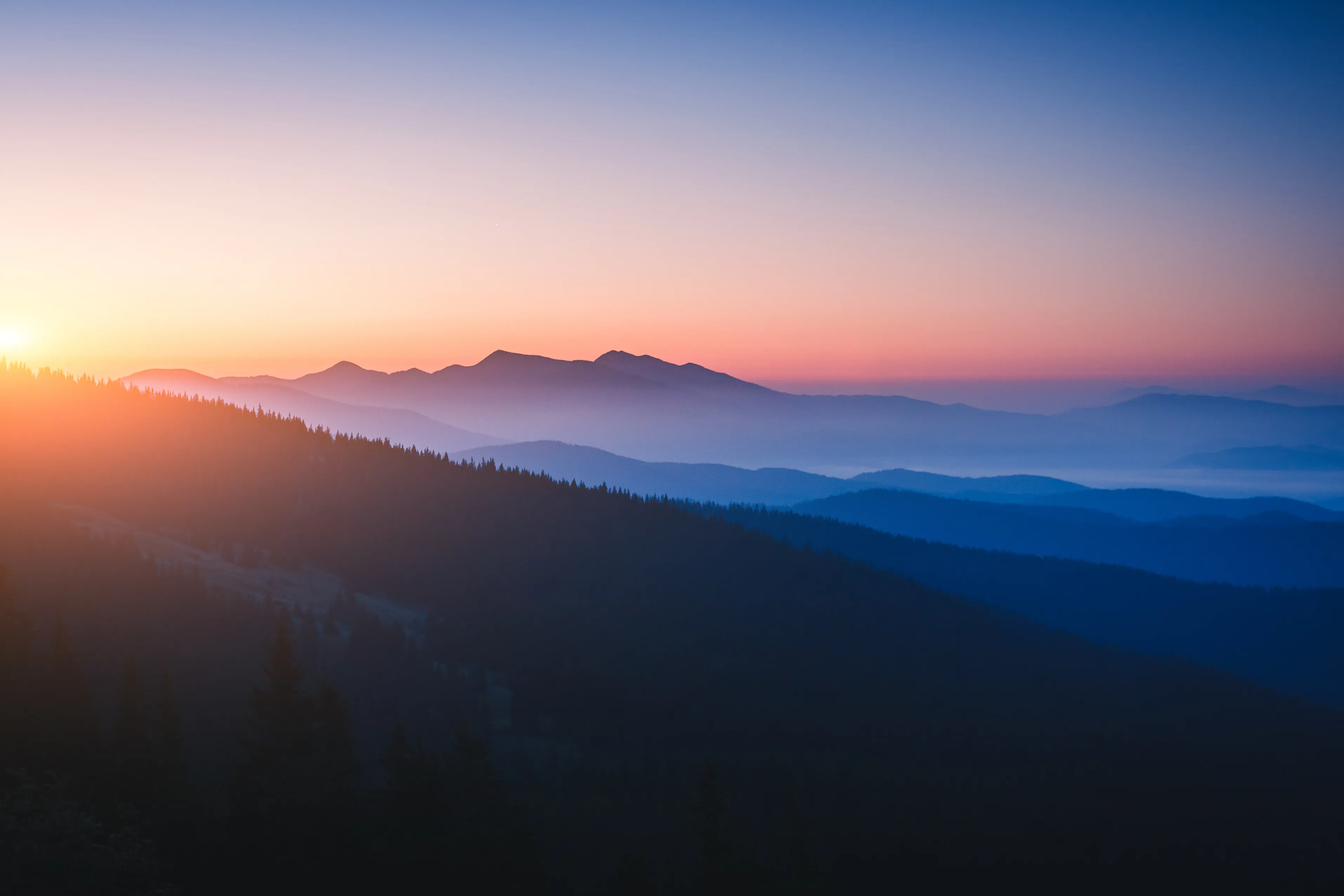 A beautiful wide-angle forested mountain range at dawn.