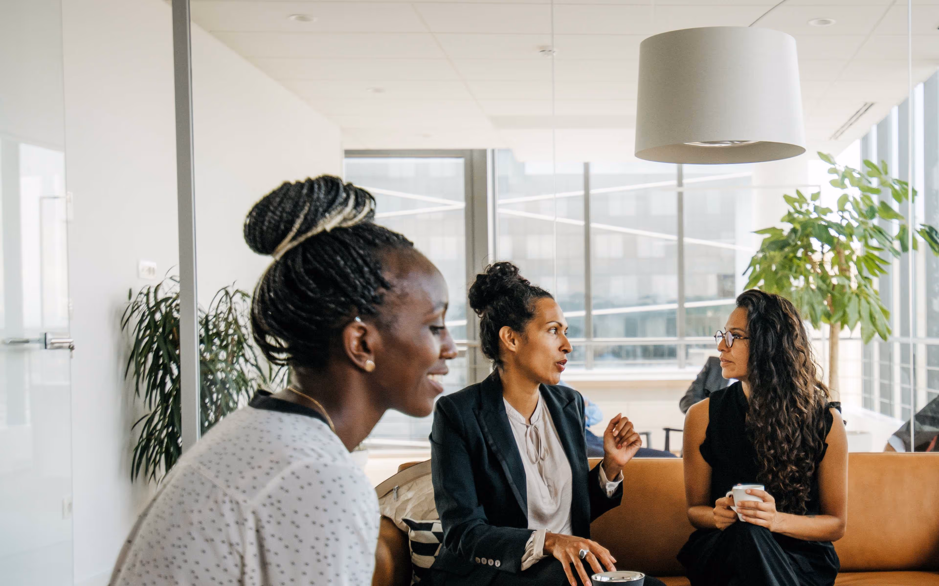 Black businesswomen working in a well-lit room, talking and focusing on work.