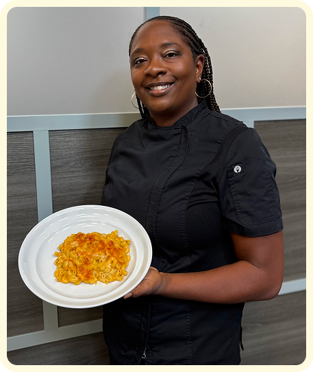 PIcture of the owner Gina holding a plate of mac and cheese.