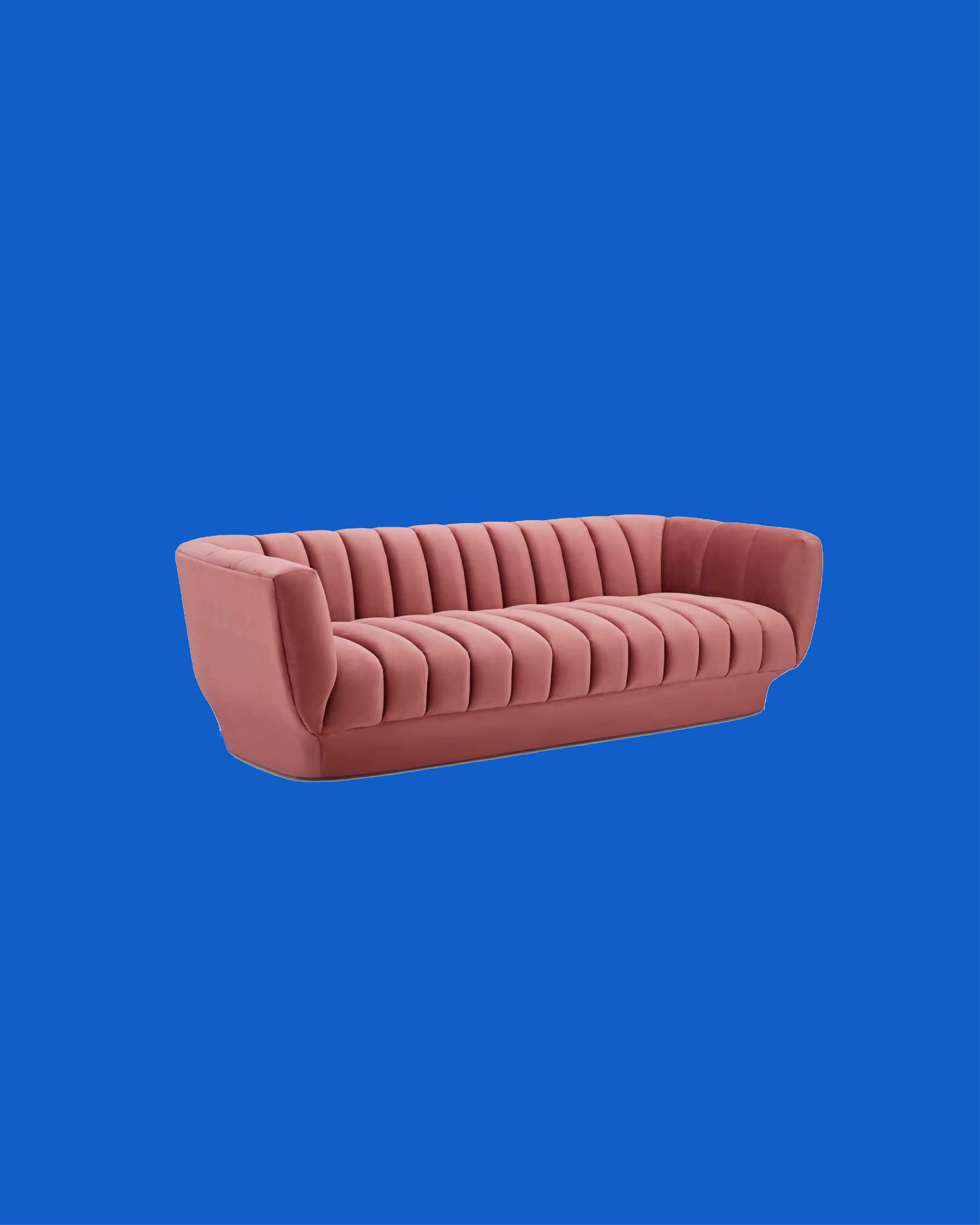 Modern pink velvet sofa with vertical channel tufting on a solid blue background.