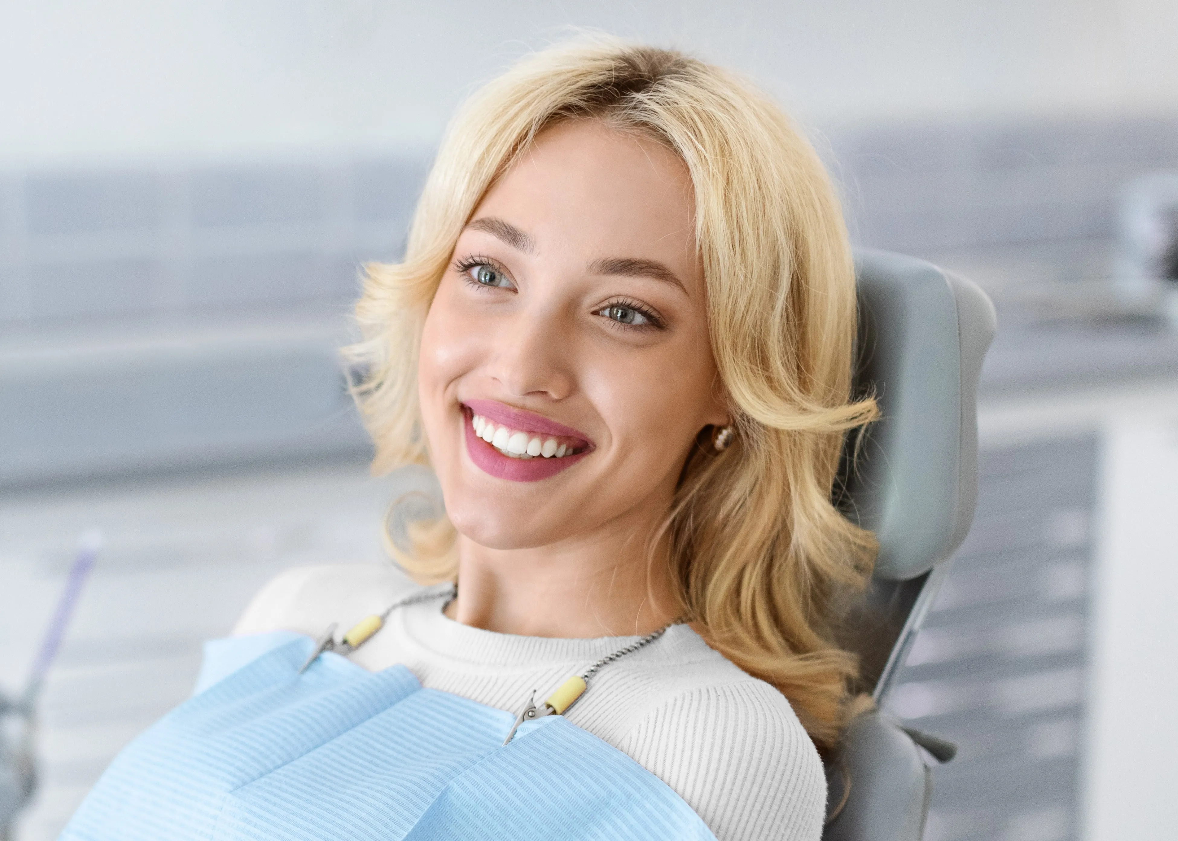 A woman sitting in a dental chair smiling.