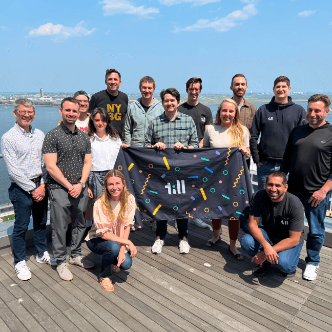 The Till Financial Team standing proudly with a banner in hand.