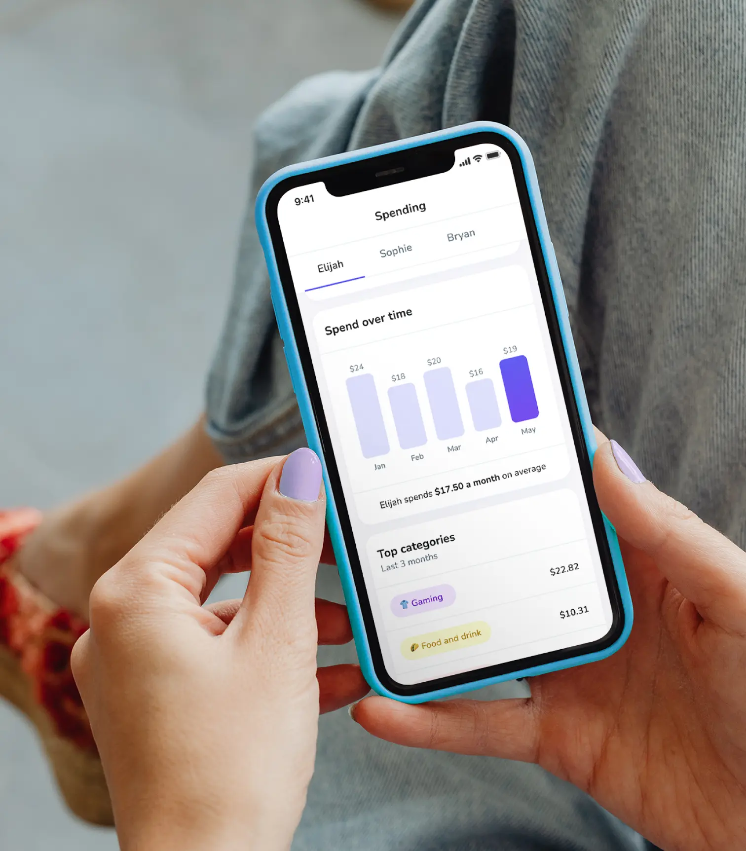 A woman holding her phone and looking at insights into how her kid spends money over time and their top spending categories