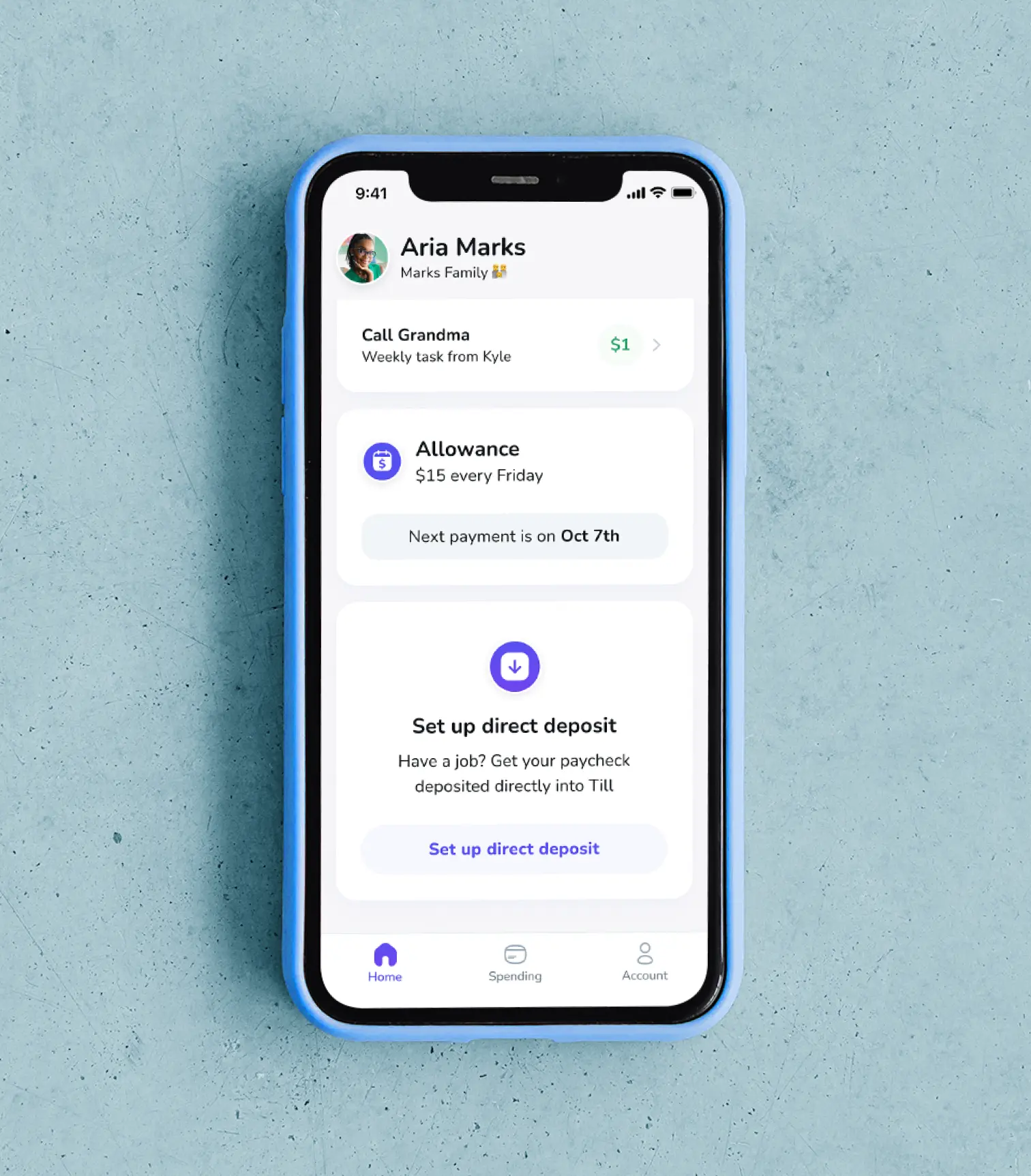 A phone laying on a blue floor. The Till app is open and showing a kids list of chores, upcoming allowance, and direct deposit.