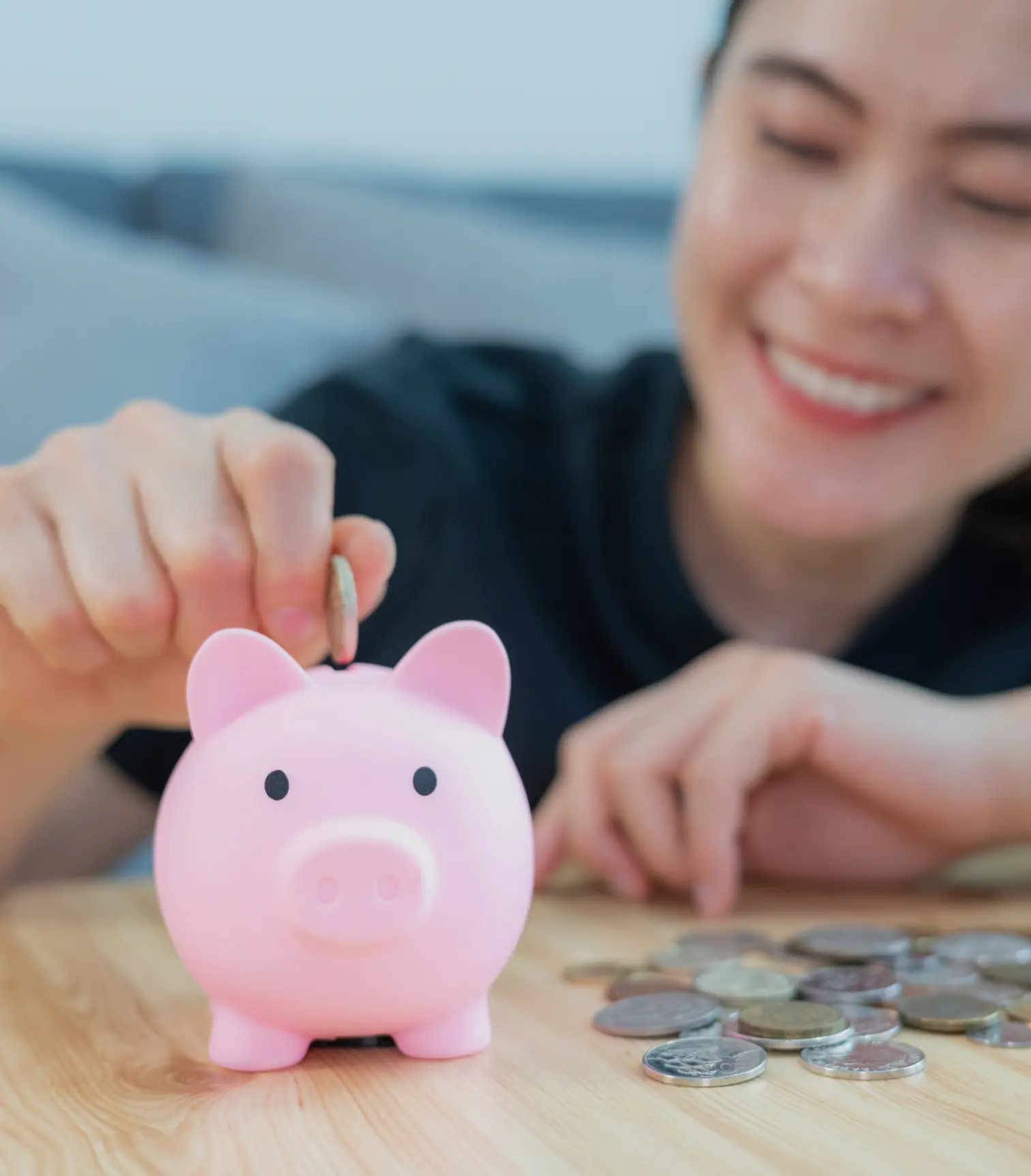 A teenage girl adding coins to a piggy bank
