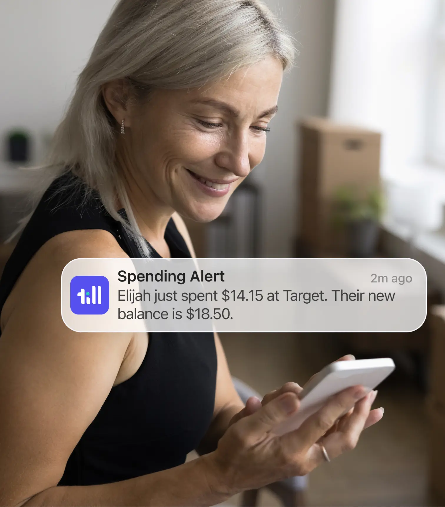 A woman looking at her phone and seeing an alert from Till saying her kid spent money at target
