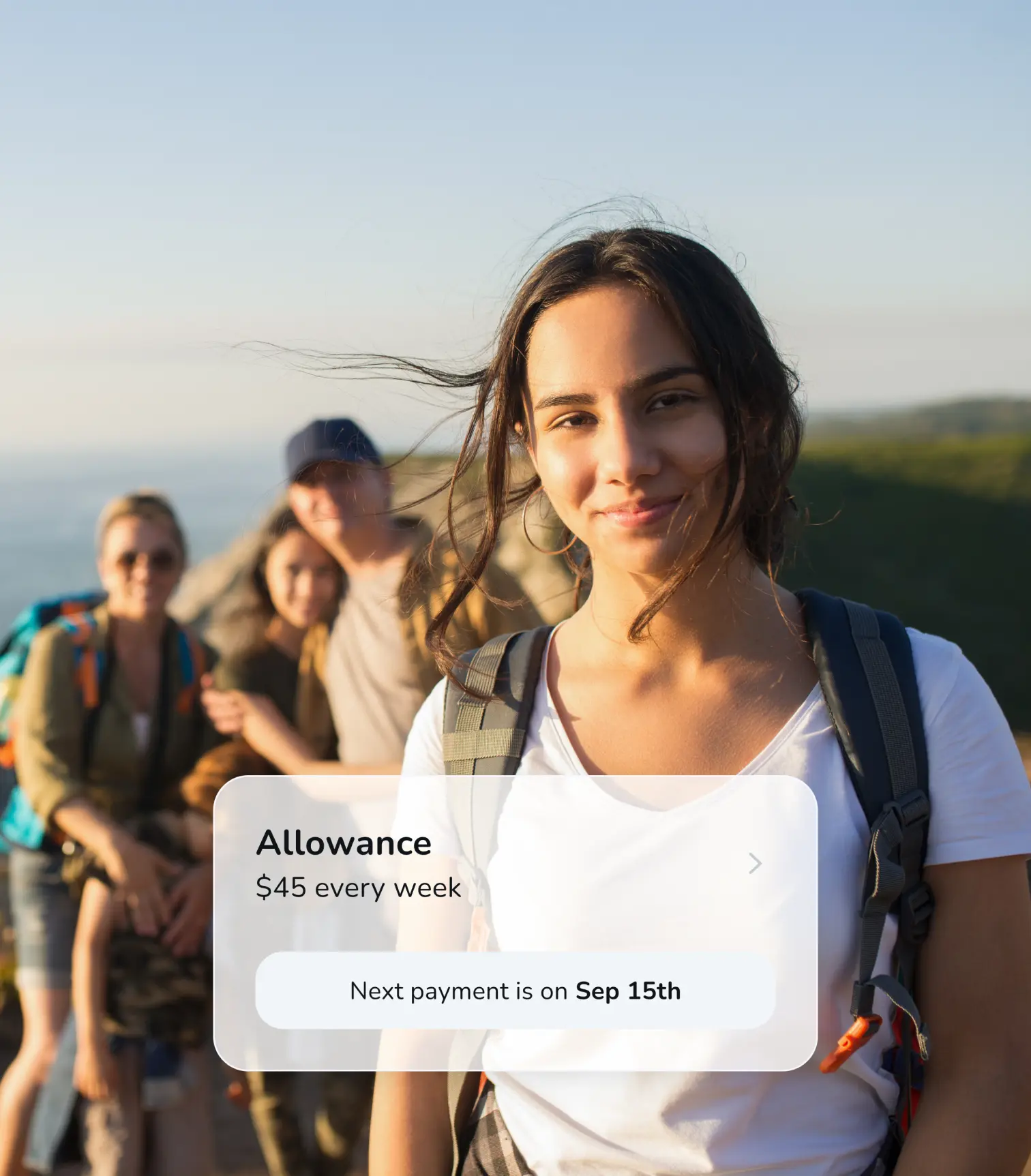 A teenage girl with her family behind her and overlayed with a UI component showing an upcoming automted allowance of $45