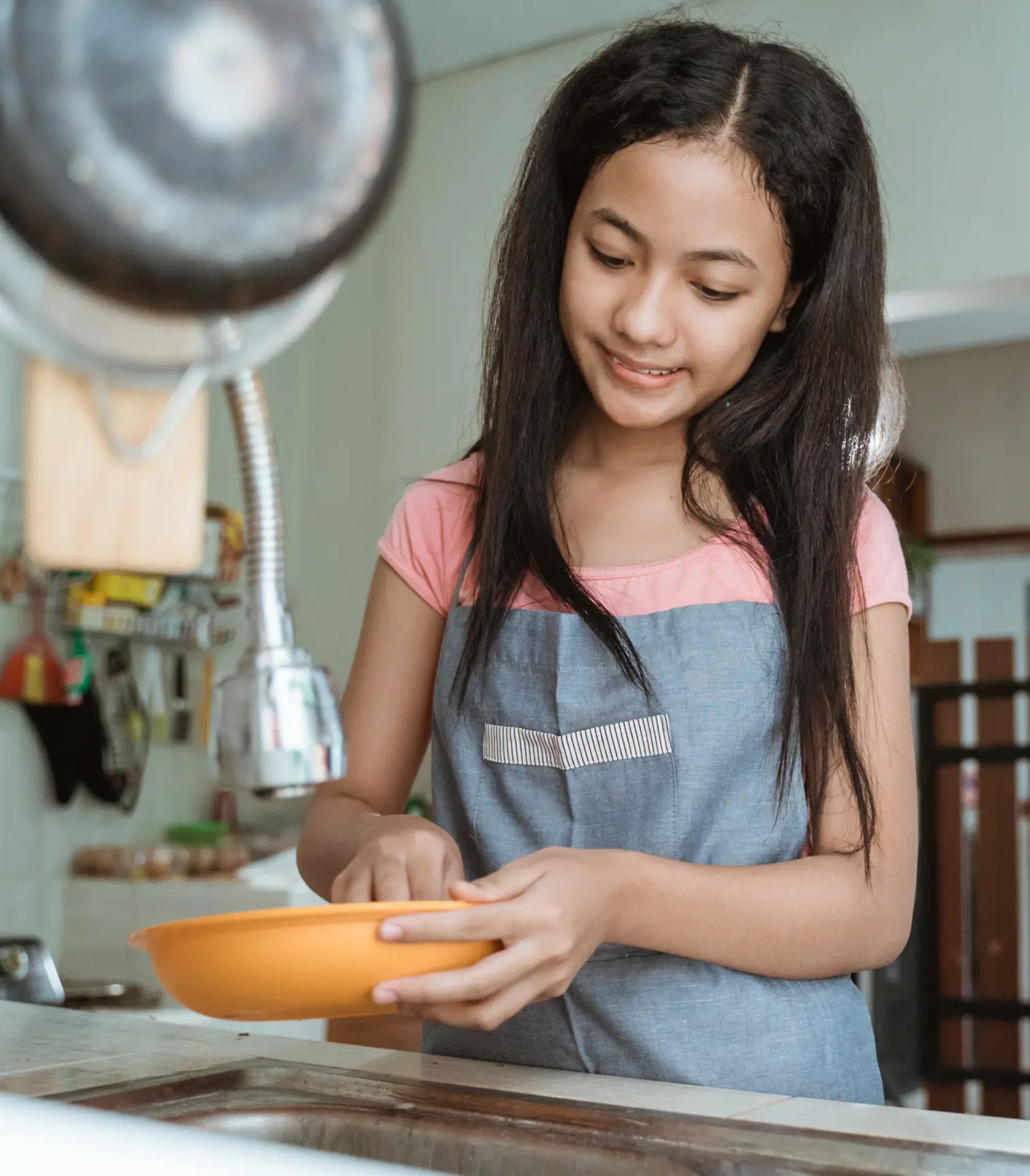 A young teenage girl doing dishes as part of her chores