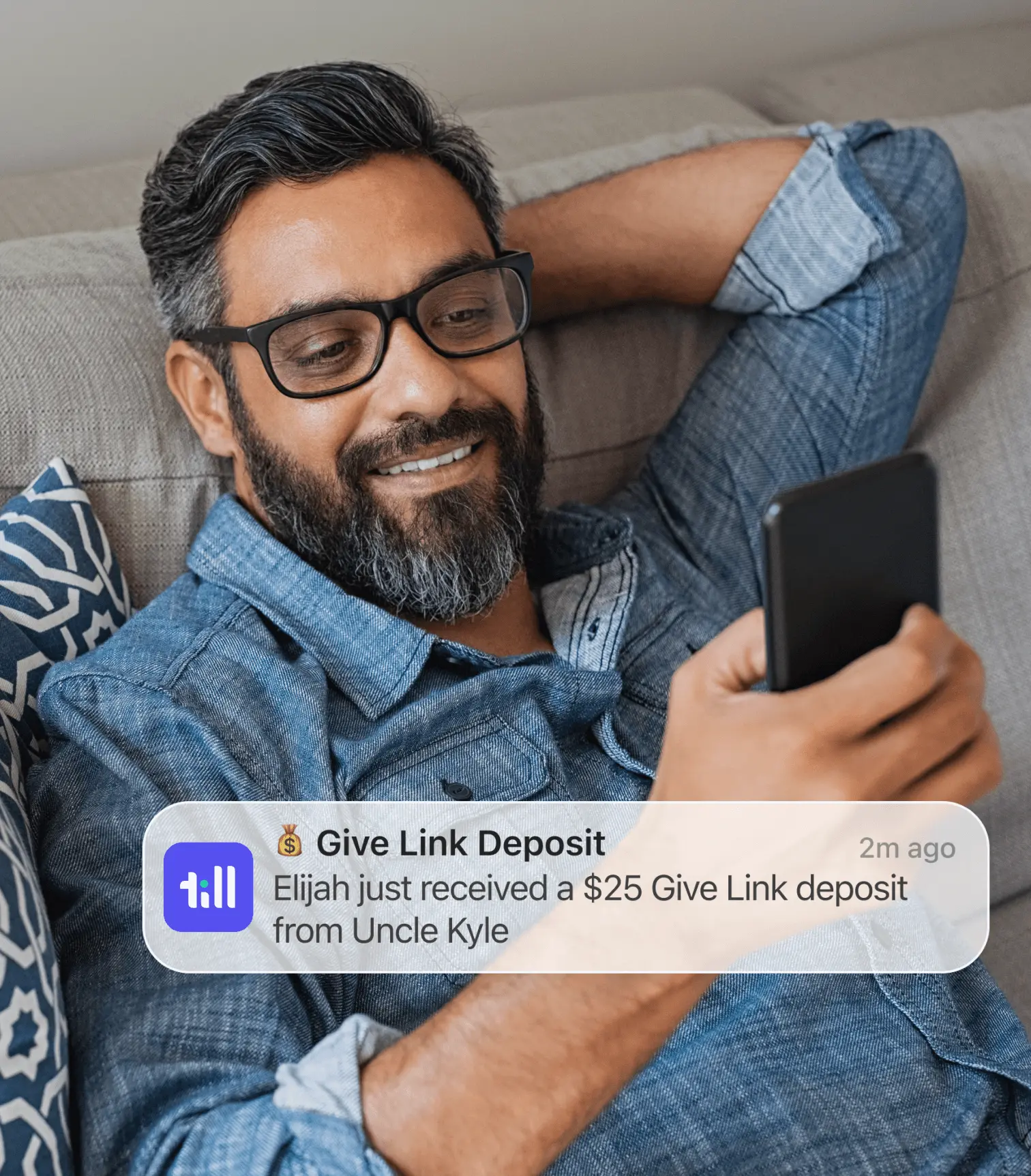A man holds his phone looking at a push notificaiton from Till letting him know his son has received money from an uncle