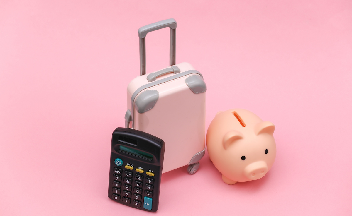 Image of a piggy bank next to a mini suitcase and calculator