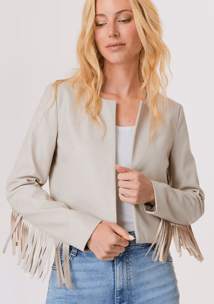 Blonde woman wearing a shiny gold short-sleeve puffer jacket with a zipper, paired with white pants.