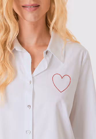 Woman with long blonde hair wearing a beige long-sleeve sweater with button details and light beige pants.