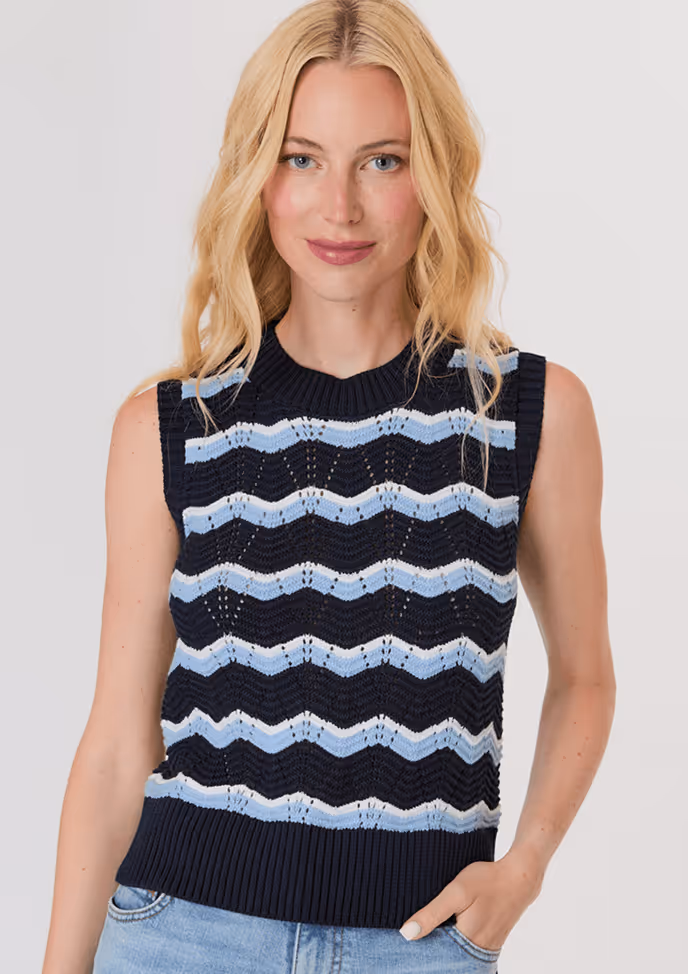 Blonde woman wearing a dark brown cropped cardigan with a satin ribbon tie over a white top and light blue high-waisted jeans.