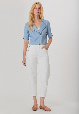 Blonde woman wearing a light gray sweater adorned with small pearls, posing against a plain light background.