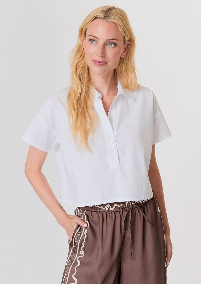 Blonde woman wearing a beige cardigan with furry cuffs and light blue high-waisted jeans.