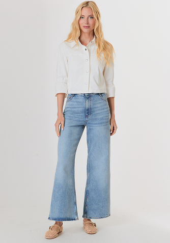 Blonde woman wearing a white short-sleeve knit top with decorative buttons and collar.