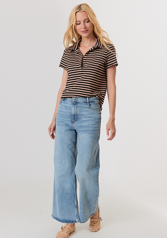 Blonde woman wearing a cream jacket with large fluffy white cuffs over a white top and white pants.