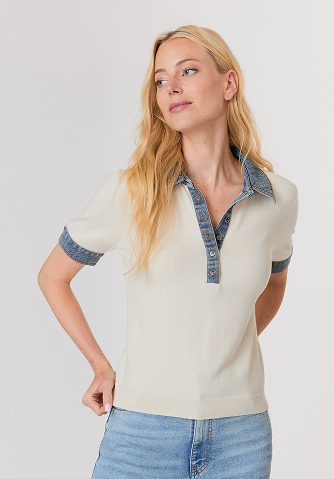 Woman with long blonde hair wearing a beige long-sleeve sweater with button details and light beige pants.