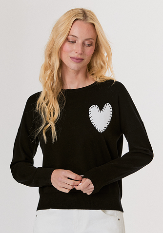 Woman wearing a black mesh sweater and a black leather midi skirt with studded high heel sandals.