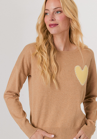 Blonde woman wearing a cream-colored cable knit sweater with a half-zip collar.