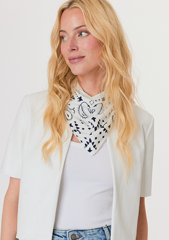 Woman wearing a red sweater with white and red star patterns, paired with white pants, standing against a light background.