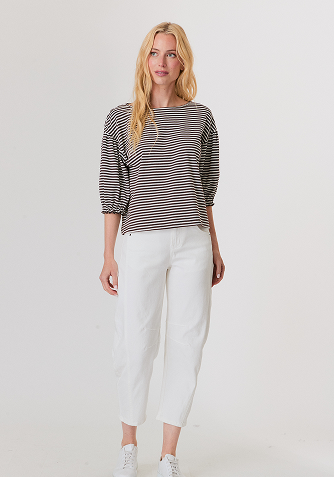 Blonde woman wearing a cream-colored cable knit sweater with a half-zip collar.