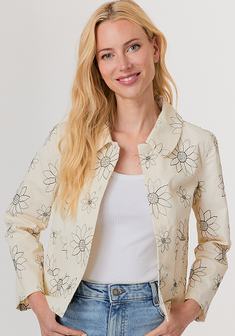 Blonde woman in a navy button-up shirt with embellished collar and light blue jeans against a plain background.
