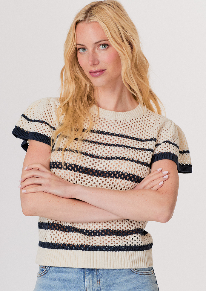 Blonde woman wearing a dark brown cropped cardigan with a satin ribbon tie over a white top and light blue high-waisted jeans.