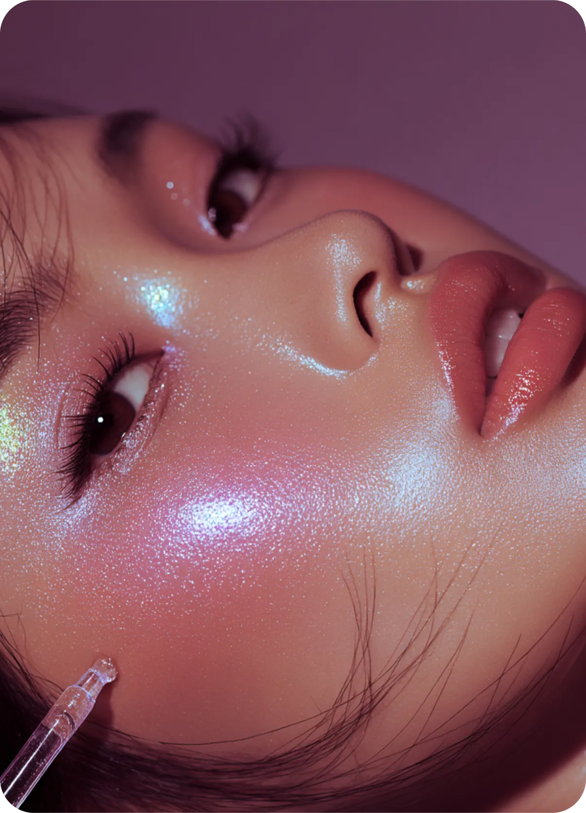 Close-up of a face with glistening skin, glossy pink lips, and a dropper applying serum on the cheek.