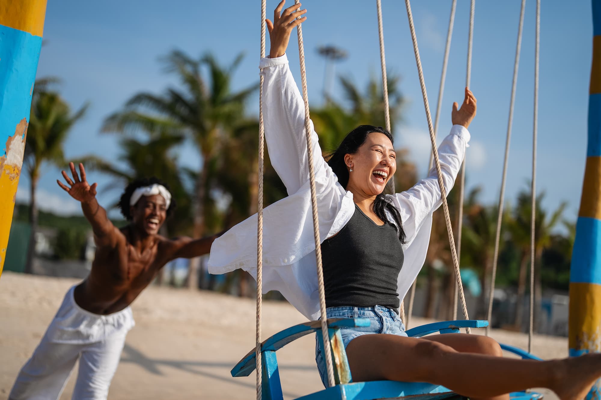 couple enjoying sunny beach on swings