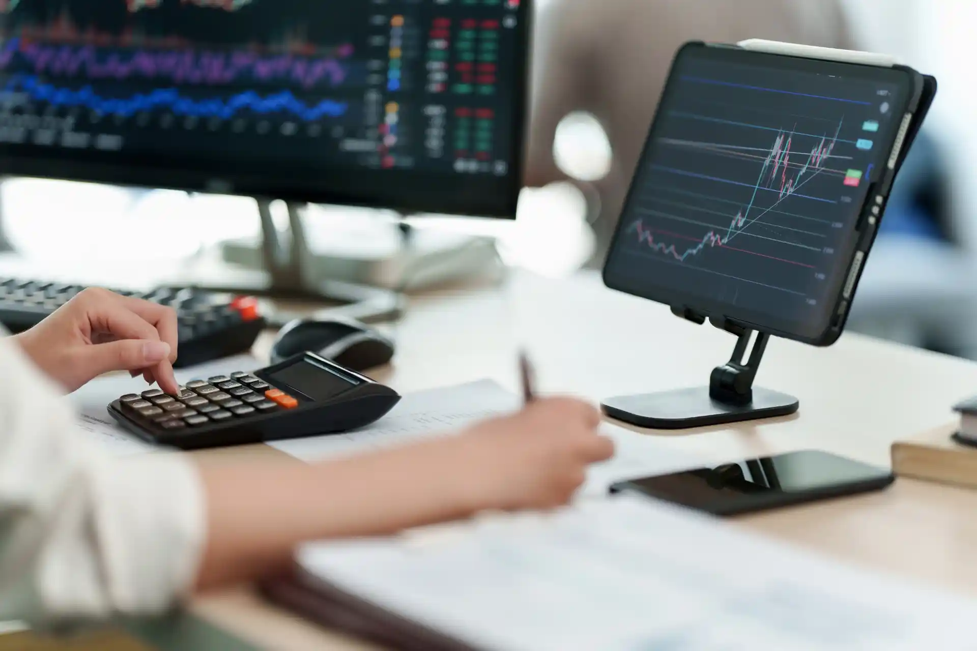 Business professional calculating financial data with charts on tablet and monitor, analyzing depreciation and tax strategy