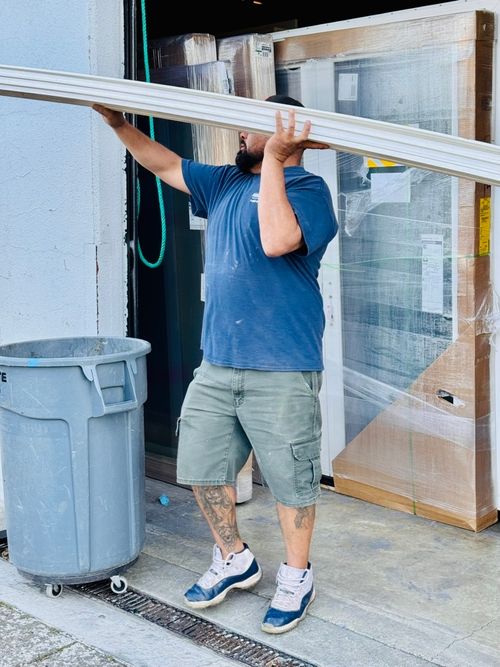 Custom Exteriors installation team member carrying exterior trim material at a job site, demonstrating hands-on craftsmanship and professional installation work.