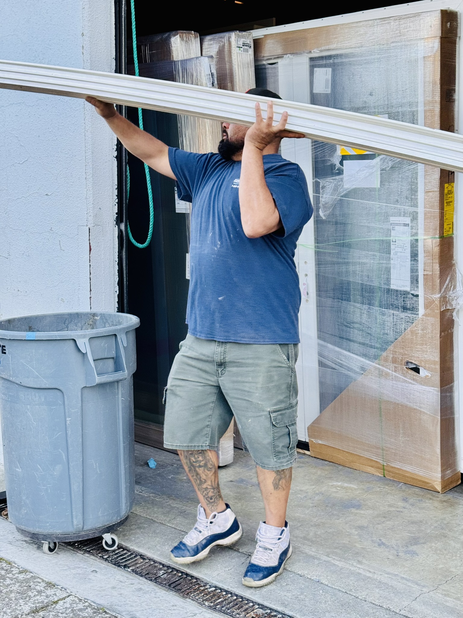 Custom Exteriors installation team member carrying exterior trim material at a job site, demonstrating hands-on craftsmanship and professional installation work.