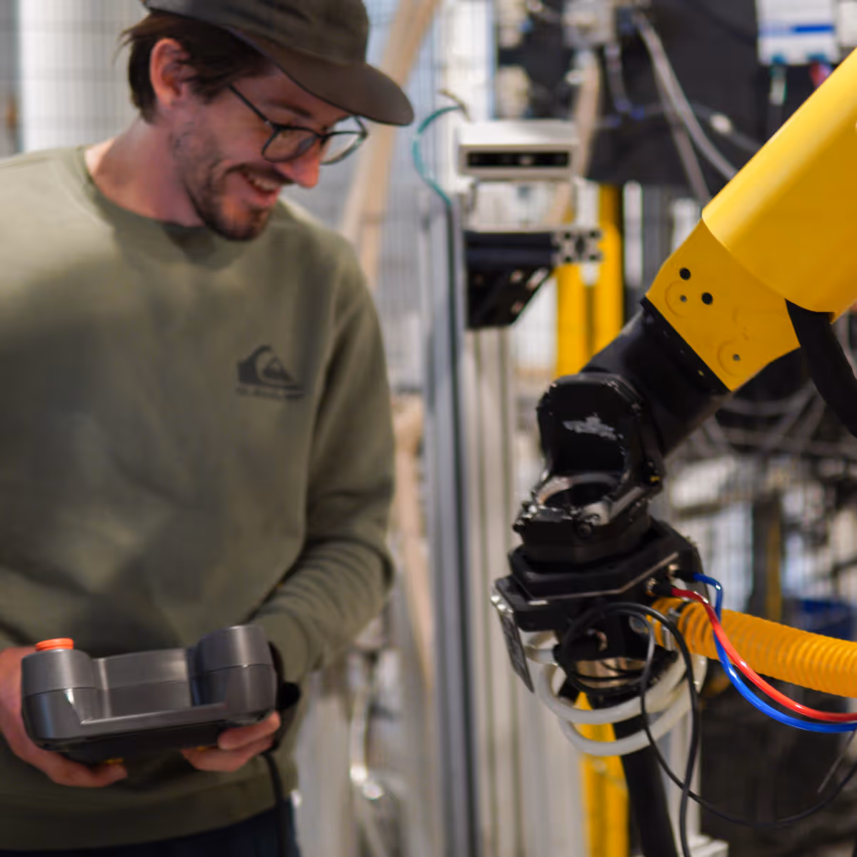 A smiling Osaro employee changing a part on a robotic arm.