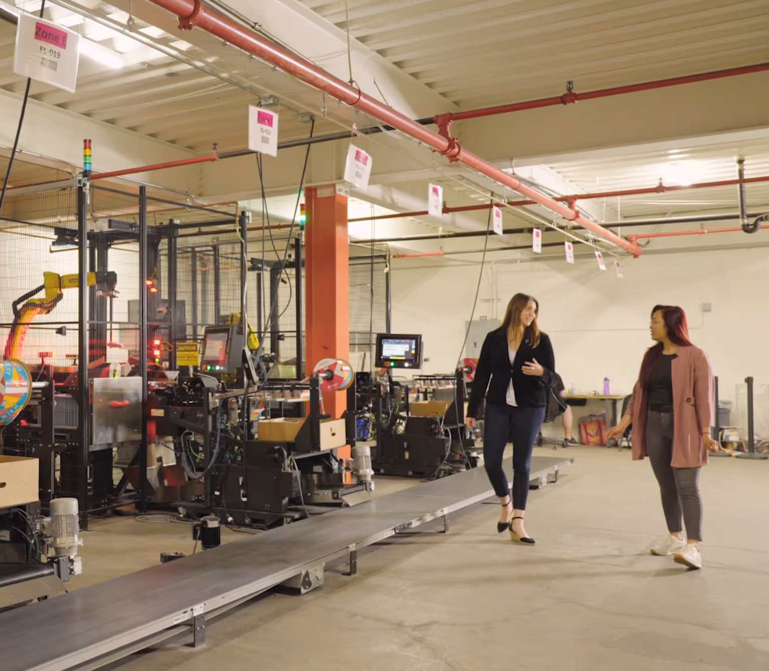 Two people walking the line of robots while talking