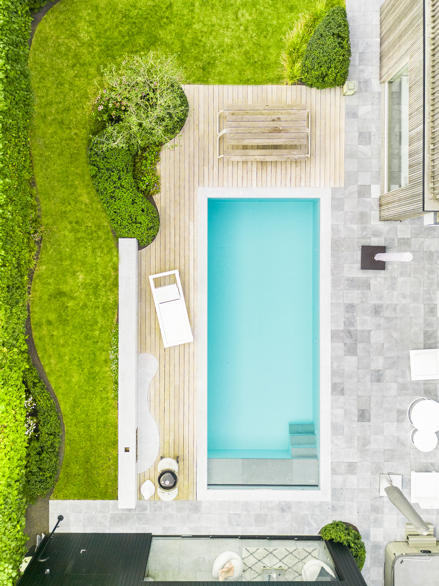 Bovenaanzicht van zwembad met houten terras en tegels rond poolhouse
