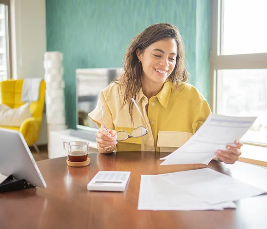 Smiling business owner reviewing incorporation documents with calculator and tablet - Tauro Accounting incorporation services