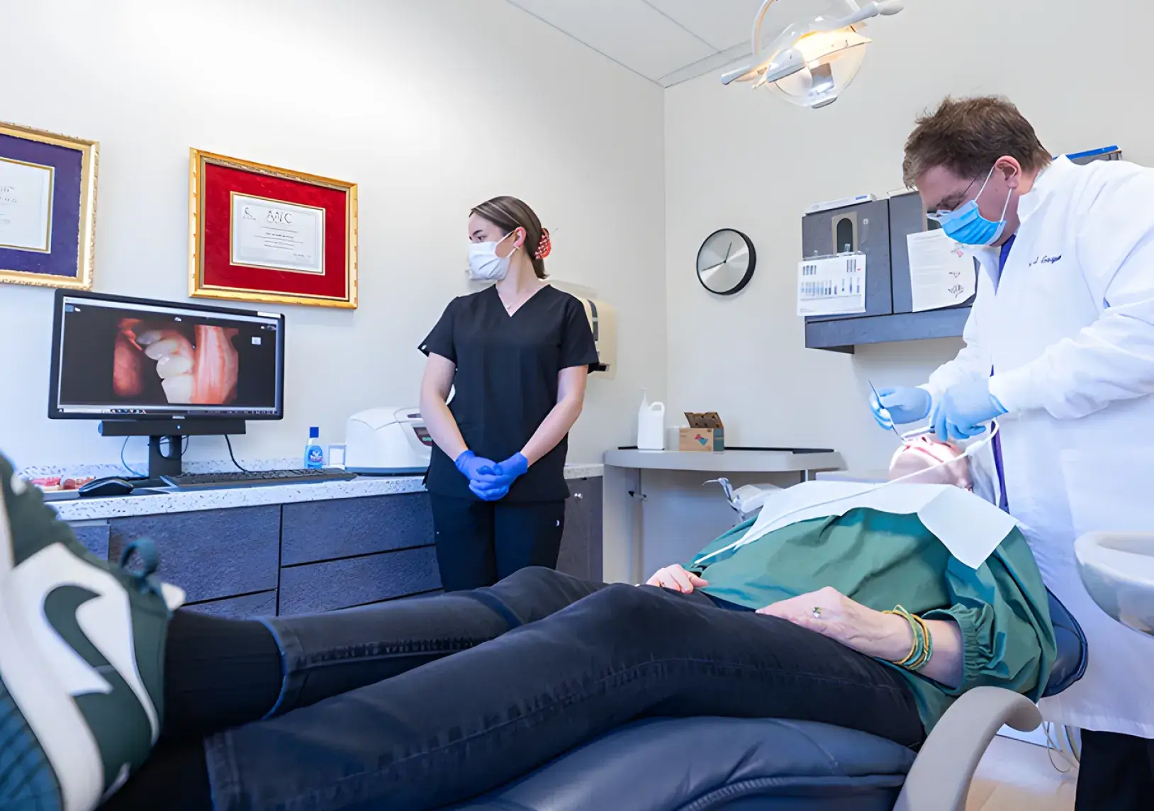 A dentist and assistant perform a dental procedure on a patient in a clinic.