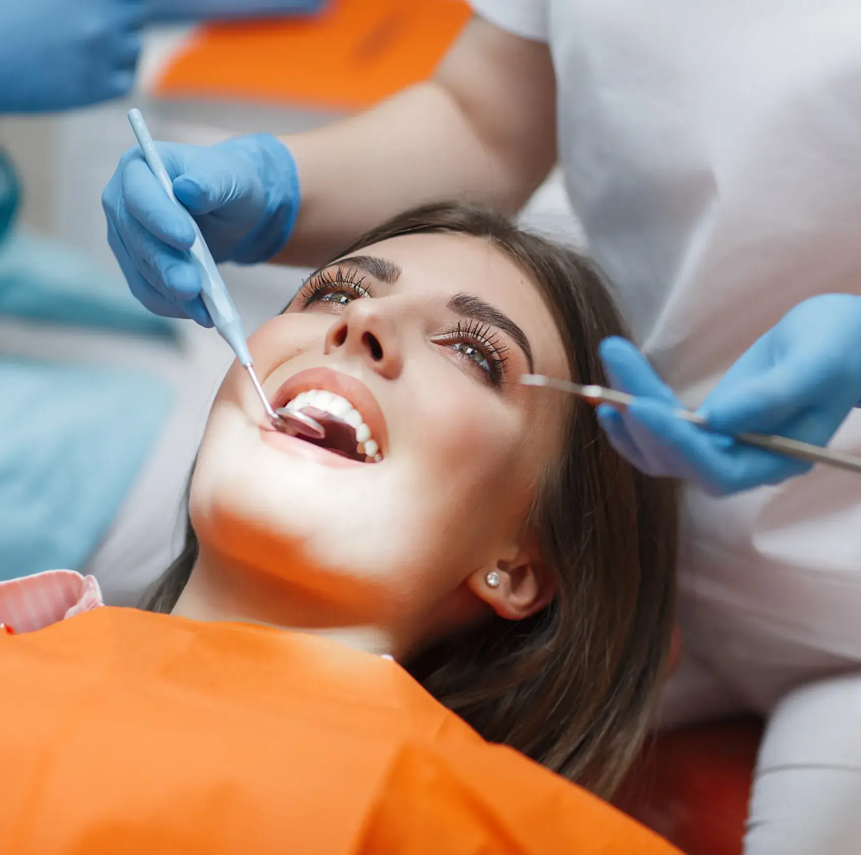 A dentist examines a patient's teeth with dental tools.